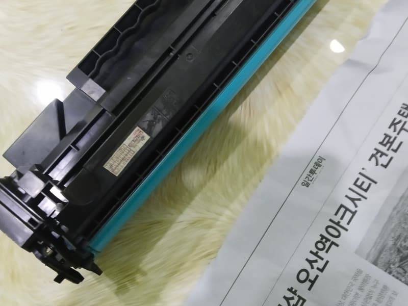 Trống cảm quang màu xanh bên trong hộp mực — bộ phận quyết định bản in có sọc hay không